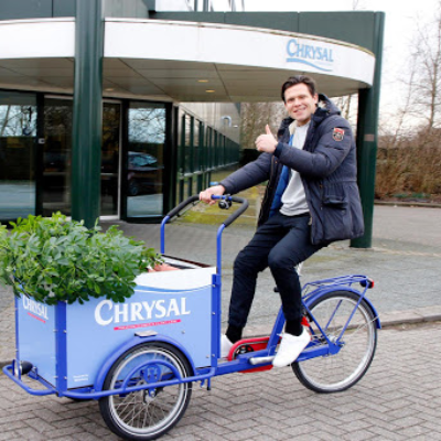 Iemand op een speciale Chrysal-bakfiets in de bedrijfskleuren blauw en wit. 